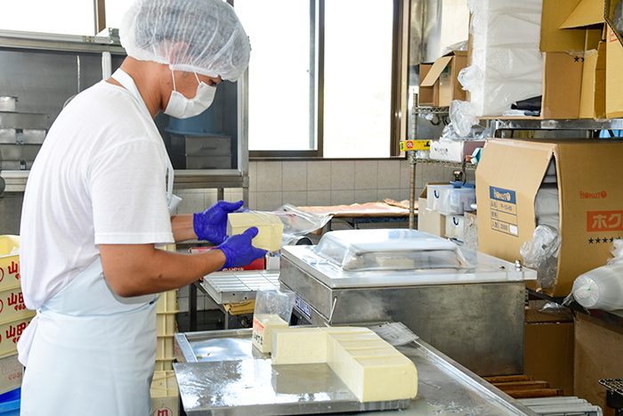 あちこーこーの豆腐は手作業で切って袋詰め。「山田とうふ店から往復1時間以内」のスーパーや商店に卸しているs