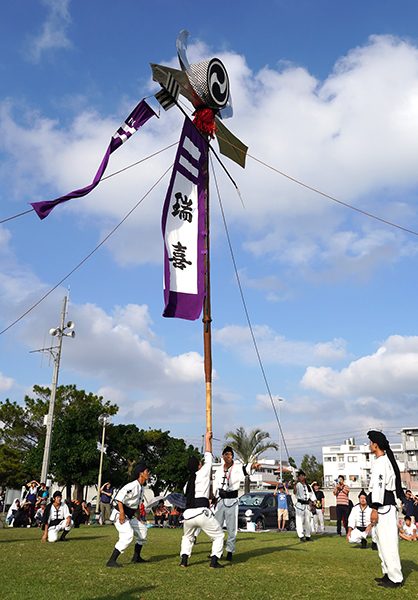 焼失から2日後、復興への思いを込めたチャリティーイベントで旗頭を高く上げる首里寒川町青年会のメンバーら＝2019年11月2日、糸満市