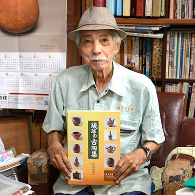 館長の伊禮信吉さん。手に持つのは2013年に発刊した「琉球の古陶集」