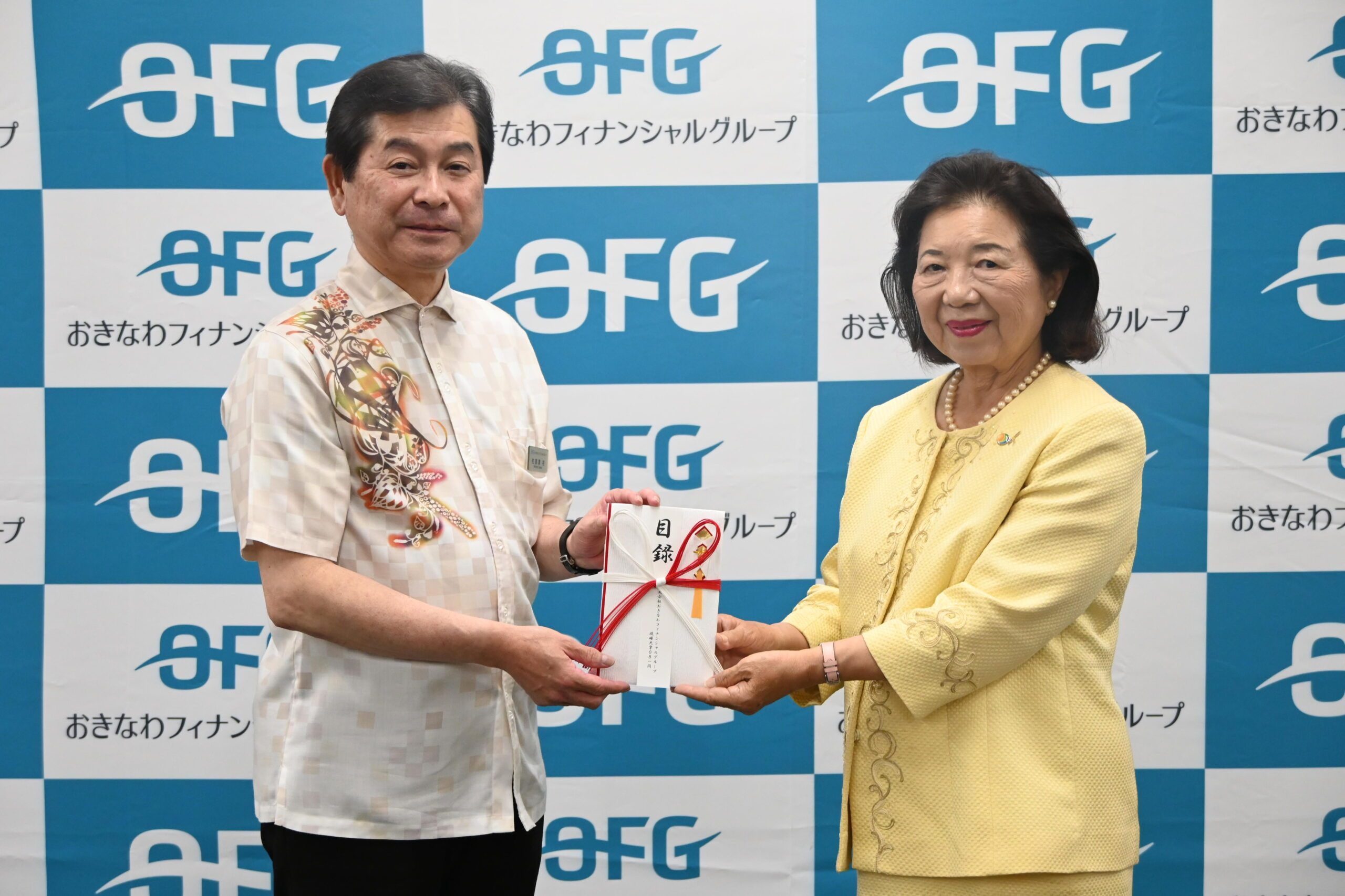 OFG琉球大学OBを代表し、寄付金を手渡す沖縄銀行の佐喜真裕常勤監査役（左）