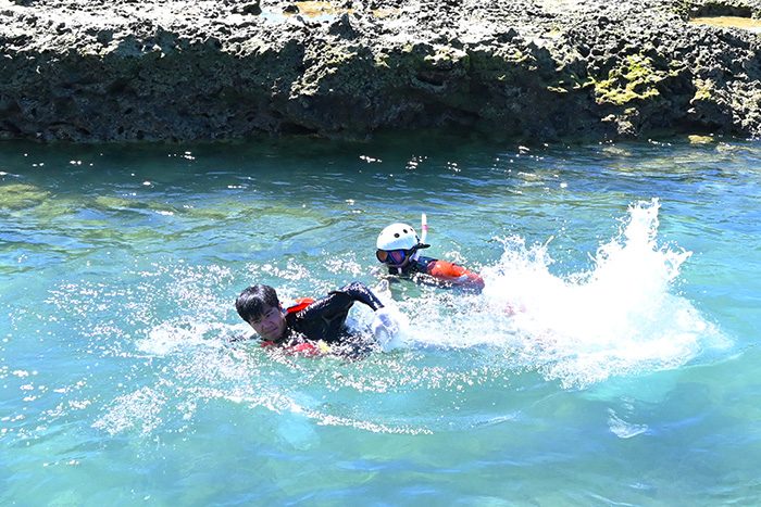 離岸流にあらがって泳ぐ名嘉記者（左）＝5日、糸満市の大度浜海岸