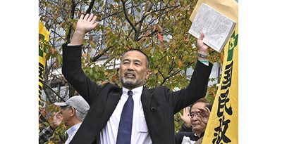 名古屋高裁金沢支部の再審開始決定を受け、決定書を高く掲げる前川彰司さん＝23日午前、金沢市